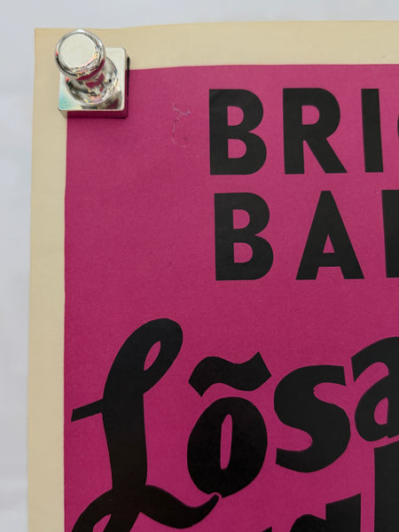 A close-up of a poster or print pinned with a silver binder clip. The design features bold black typography on a vibrant magenta-pink background, bordered by a cream-colored margin.